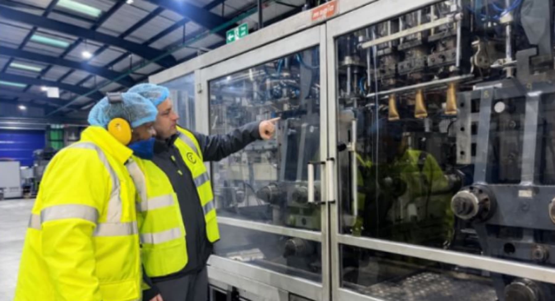 A First Circle engineer showing a colleague a blow-moulding machine
